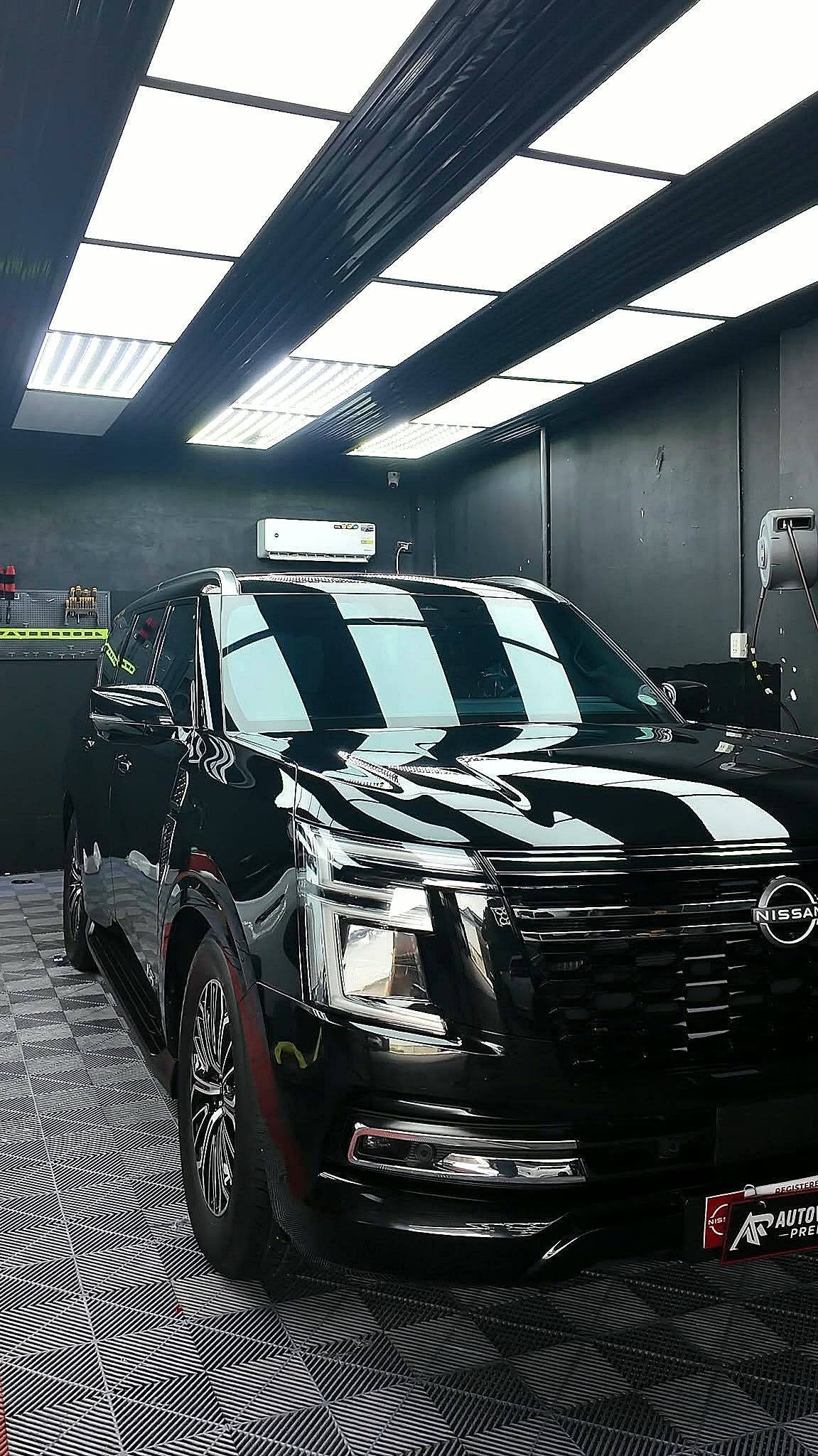A black Nissan Patrol finished and parked in the AR Autoworks bay, ceiling lights reflected cleanly down the flank