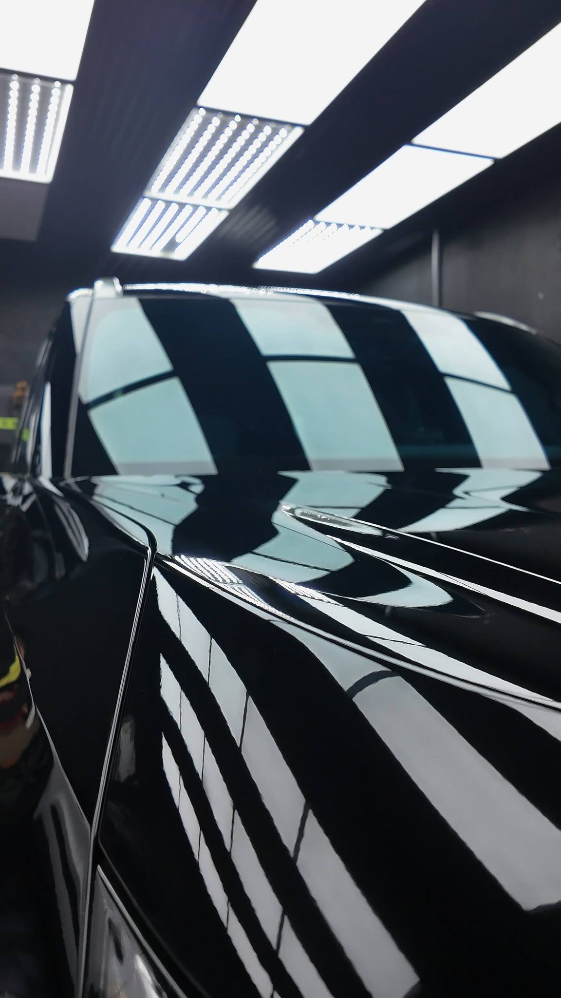 Ceramic-coated black paintwork with the bay ceiling lights reflected in an unbroken line across the roof and shoulder